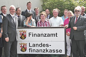 Im Beisein von Mitarbeitern enthüllen der Oberfinanzpräsident, Werner Nägler (rechts), und der Leiter der neuen Behörde im Behördenzentrum Daun, Klaus Fischer (links), das Türschild der am 1. Juli 2013 gegründeten Landesfinanzkasse.