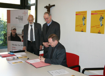 Generalvikar Dr. Georg Bätzing unterschreibt im Beisein von Hans Casel und Winfried Görgen die Stiftungsurkunde.