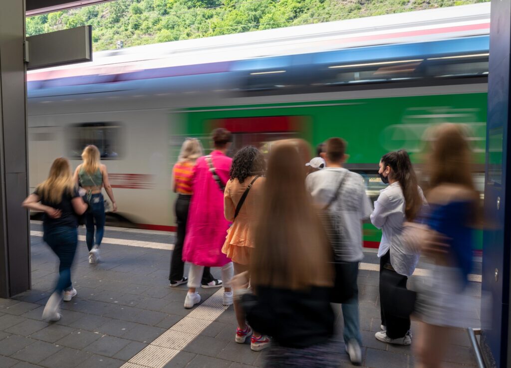 Verschwommene Aufnahme von Menschen, die am Bahnsteig zu einem einfahrenden Zug gehen.