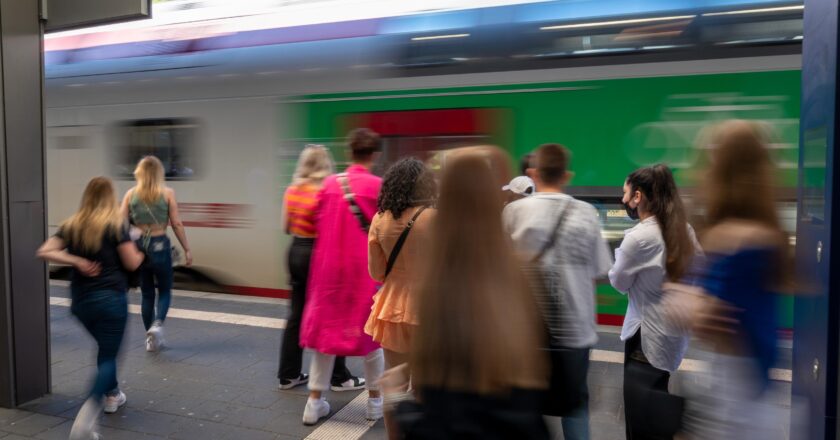 Verschwommene Aufnahme von Menschen, die am Bahnsteig zu einem einfahrenden Zug gehen.