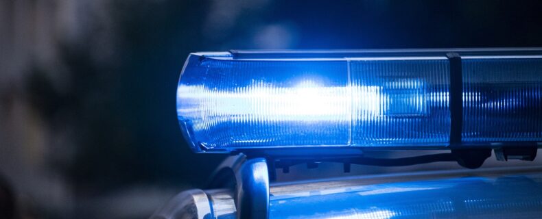 Leuchtendes Blaulicht eines Polizeiautos in Nahaufnahme bei Nacht.