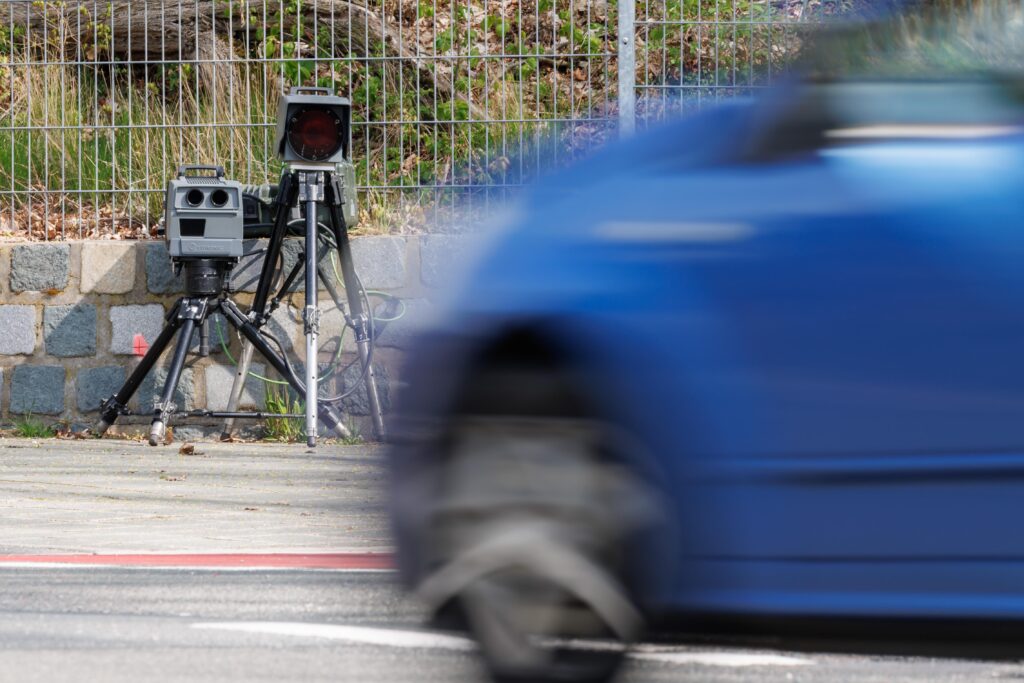 Eine Radarfalle steht am Straßenrand und überprüft die Geschwindigkeit vorbeifahrender Autos.