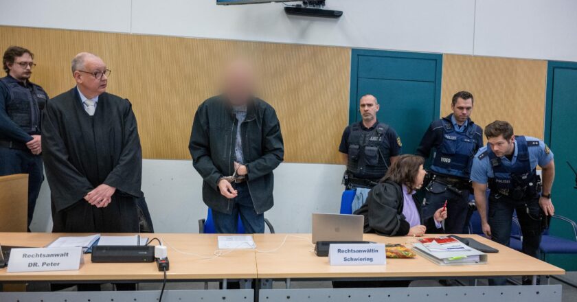 Der Amokfahrer von Trier steht im Gerichtssaal umringt von seinen Verteidigern und Sicherheitspersonal.