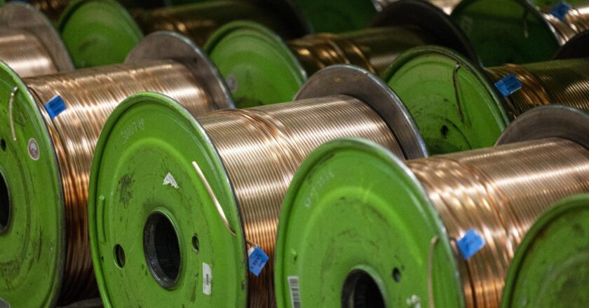 Kabeltrommeln mit Kupferkabeln liegen nebeneinander in einer Produktionshalle.