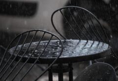 Regen prasselt auf einen Tisch eines Cafés im Außenbereich.