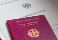 Ein Einbürgerungsurkunde der Bundesrepublik Deutschland und ein deutscher Reisepass liegen auf einem Tisch.