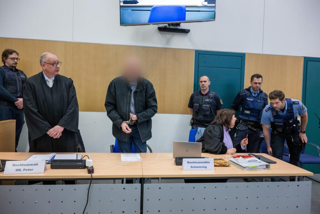 Der Trierer Amokfahrer steht im Gericht, umgeben von seinen Anwälten und Gerichtspersonal.